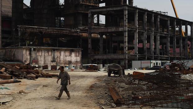 A worker walks past partly demolished buildings at the plant.