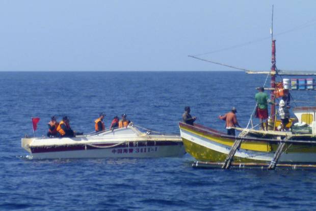 In this Feb. 27, 2015, photo provided by Filipino fisherman Renato Etac, Chinese Coast Guard members approach Filipino fishermen near Scarborough Shoal in the South China Sea.