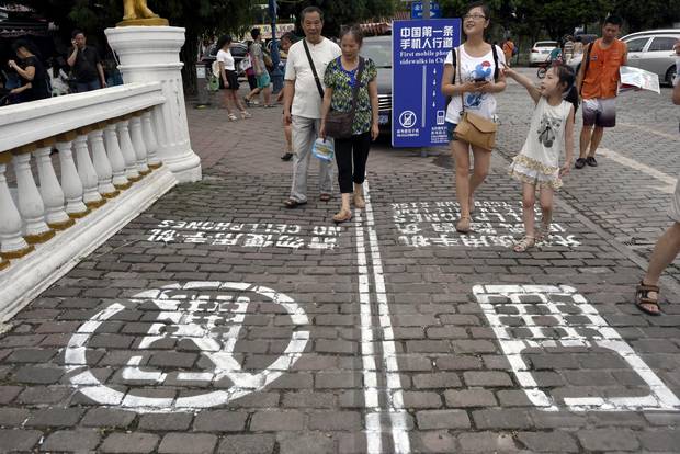 Residents walk on a lane painted with instructions to separate those using their phones as they walk from others in southwest China's Chongqing municipality.