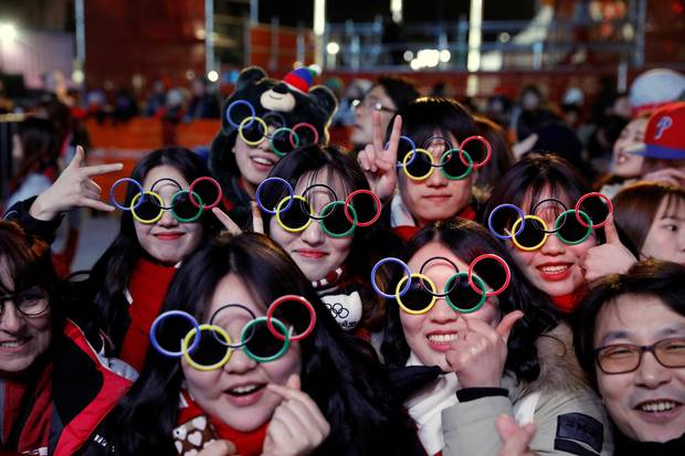 Volunteers pose for photographs during a medal ceremony at the Medal Plaza in Pyeongchang, on Feb. 18, 2018.