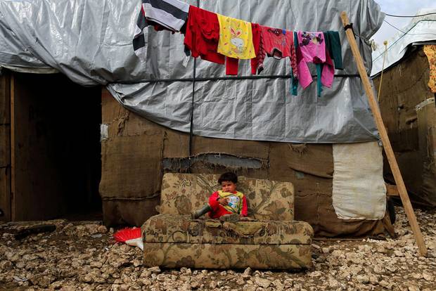 A Syrian refugee child sits on a sofa outside her family's tent at a refugee camp in the town of Hosh Hareem, in the Bekaa valley, east Lebanon, Wednesday, Oct. 28, 2015.