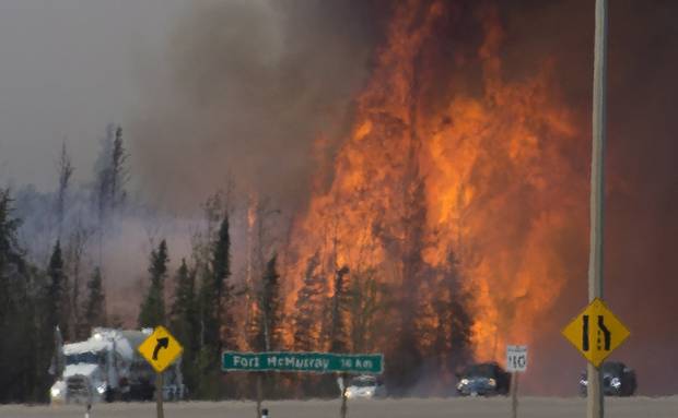 Cars and trucks try and get past a wildfire 16 km south of Fort McMurray last May.