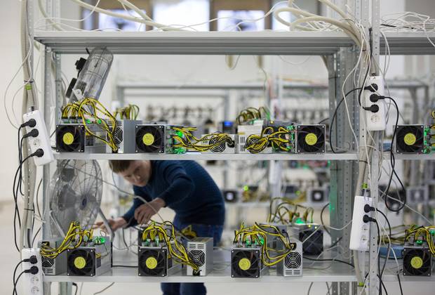 An employee checks power supply units and cooling fans used in cryptocurrency mining machine systems at the SberBit mining 'hotel' in Moscow, Russia, Dec. 9, 2017.