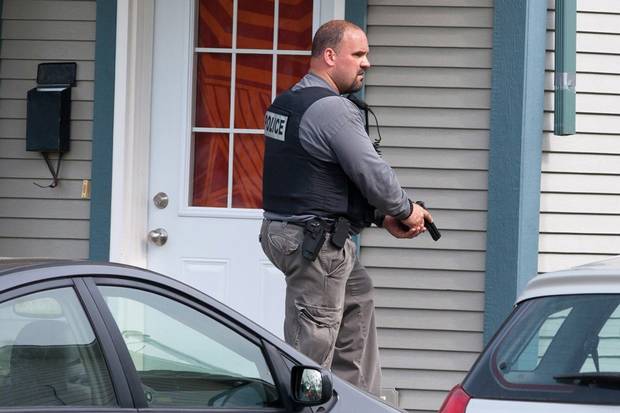 An RCMP officer surrounds a house in Moncton, N.B., June 5, 2014 as police search for a gunman a day after the rampage.