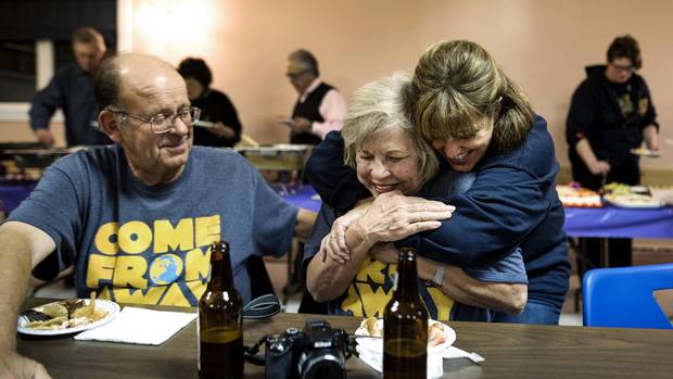 Diane Marson, centre, receives a hug from actress Sharon Wheatley, who plays her in the musical Come From Away, as husband Nick looks on.