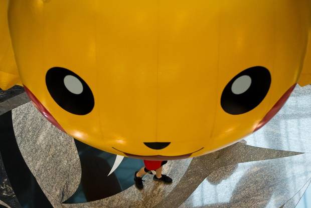 A boy walks under an oversized inflatable of Pokemon character Pikachu hanging at the Vancouver Convention Centre during the 2013 Pokemon World Championships in Vancouver, August 11, 2013.