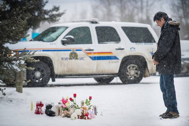 Cody Montgrand leaves a prayer candle at a makeshift memorial for the victims of the La Loche school shooting.