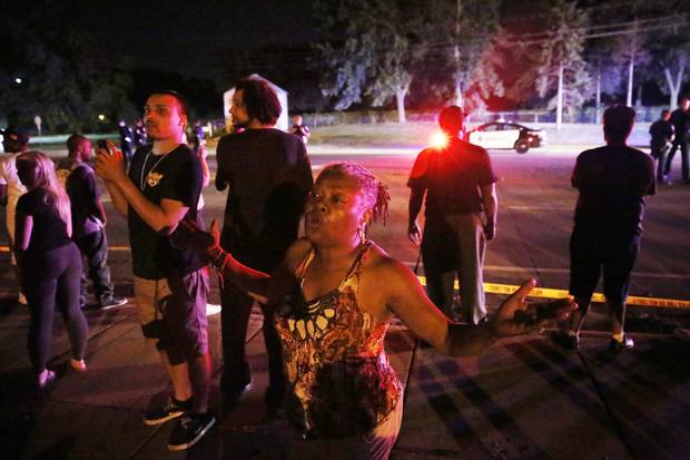 A woman joins others gathered at the scene of a police involved shooting on July 6, 2016, in Falcon Heights, Minn.