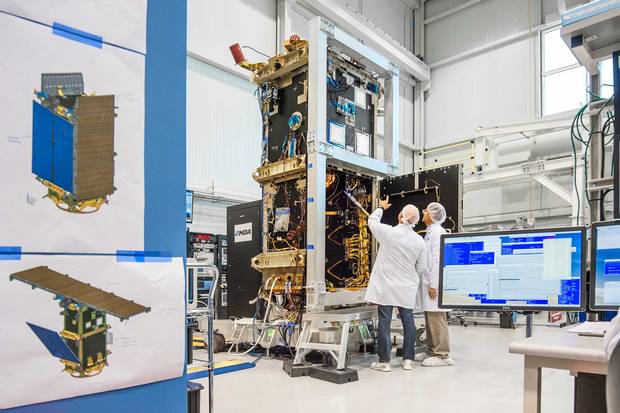 Flight assemblers install components in the satellite's bus module which will be fitted with a solar array and antennae before blast off