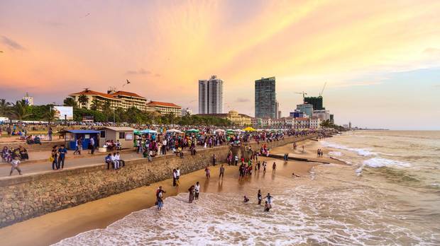 A large crowd enjoys the sunset on Galle Fort Road on the seafront of Colombo, the capital city of Sri Lanka.