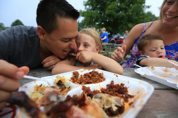 The Ugarte clan including dad, Juande, daughter, Skyanne, 3.5 baby, Ethan and mom, Ashley enjoy their rib dinners at the St. Thomas, Ribfest on Saturday July 25, 2015. 