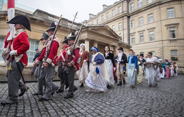 Participants in the annual Jane Austen Regency Costumed Parade pass the Thermae Bath Spa on September 10, 2016 in Bath, England. 