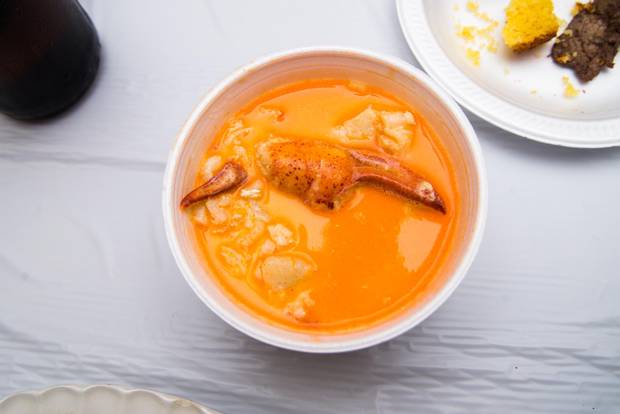 A plump lobster claw peeks out from a bowl of seafood chowder.