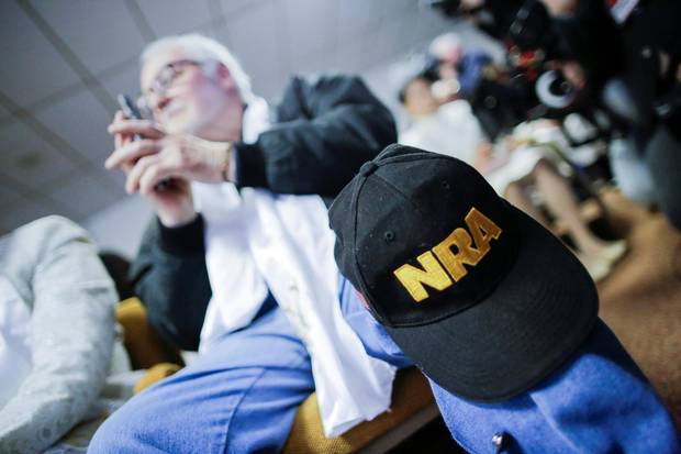 A man with a NRA cap holds his gun while people pray during a blessing ceremony at the Sanctuary Church in Newfoundland, Pa., on Wednesday.