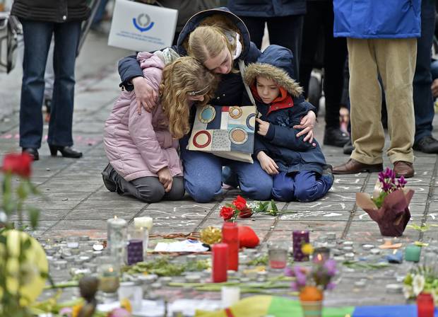 In Brussels, a woman and children sit and mourn for the victims of the bombings.