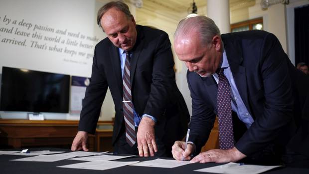 BC Green Leader Andrew Weaver, left, and NDP Leader John Horgan sign an agreement that likely spells the end of Premier Christy Clark's BC Liberal government.