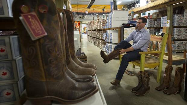 Doug Schweitzer, a leadership candidate for the united conservative party in Alberta, tries on Stampede clothes including new cowboy boots at Irvines western store near Crossfield, Alta.