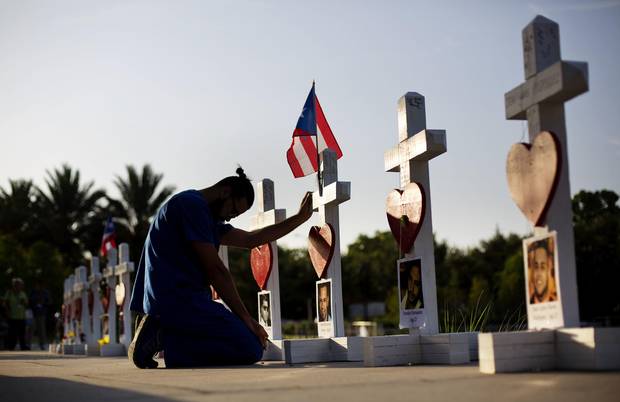 Ernesto Vergne prays at a cross honoring his friend Xavier Emmanuel Serrano Rosado and the other victims at a memorial to those killed in the Pulse nightclub mass shooting a few blocks from the club early Friday, June 17, 2016, in Orlando, Fla.