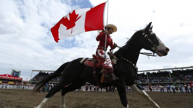 A Calgary Stampede ranch girl carries the Canadian flag to start the rodeo at the Calgary Stampede in Calgary, Alberta, July 5, 2015.