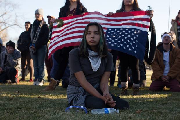 A young woman listens to speakers after a march in Bismarck, N.D., in November. Demonstrators, blocked by riot police, stood and prayed quietly for several hours before peacefully marching away.