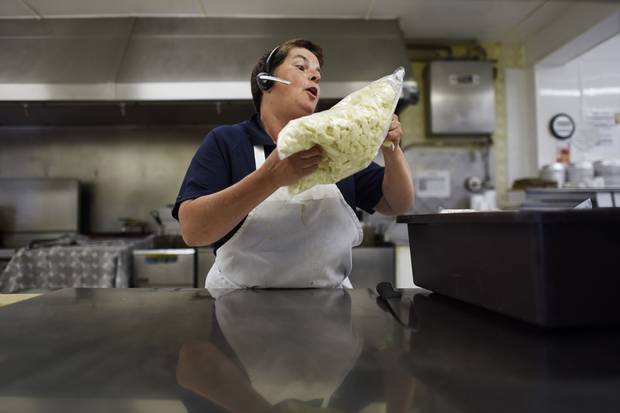 Nathalie Bergeron uses a chef's knife to break up large bags of cheese curds at the Restaurant Princesse in Princeville, Que.