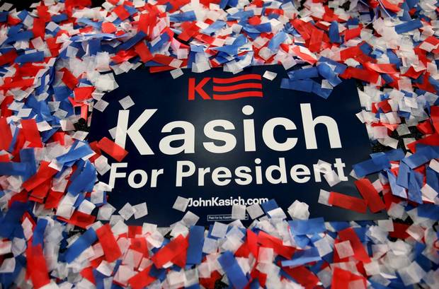 A John Kasich for president campaign sign is buried in confetti in Berea, Ohio.