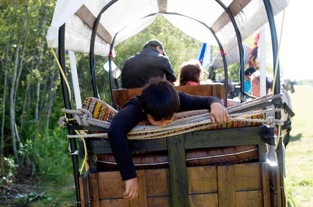 Nolan Jong waits in the back of a wagon for the Driftpile First Nation caravan to make the final journey to Lac Ste Anne, Alberta on Sunday, July 19, 2015. Members of Driftpile First Nation traditionally made the trip by horse and people have reestablished the practice for the last 15 years.