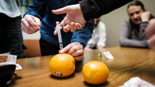 Participants in a naloxone training session in Vancouver's Downtown Eastside inject syringes into oranges as practice for treating a drug user suffering an overdose.