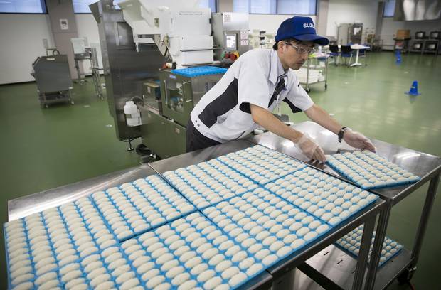 An employee places a tray of sushi rice made by a Suzumo machine on a table at a factory in Saitama, Japan in August. Suzomo’s machines are used by about 70,000 customers around the world.