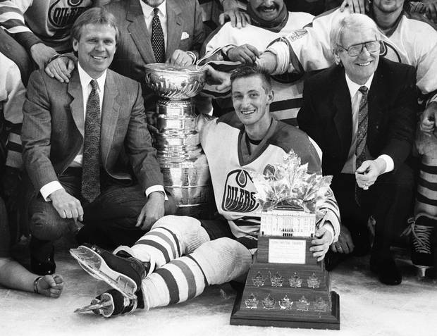 Glen Sather, left, sits with Wayne Gretzky of the Edmonton Oilers on May 26, 1988, after Edmonton defeated the Boston Bruins to win the Stanley Cup. At right is assistant coach John Muckler.