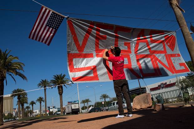 A man writes a note on a 'Vegas Strong' banner at the south end of the Las Vegas Strip.