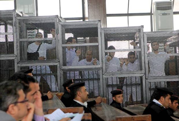 Al Jazeera English bureau chief Mohamed Fahmy, left, producer Baher Mohamed, second left, and correspondent Peter Greste, middle, stands inside a defendants’ cage with others in Egyptian courtroom on March 5, 2014.