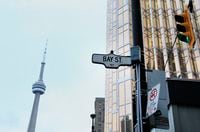 The CN Tower stands in the distance of a Bay Street sign displayed in Toronto on Tuesday, Feb. 5, 2013.