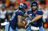 Toronto Argonauts quarterback Nick Arbuckle (9) hands the ball off to running back D.J. Foster (29) in the first half of their CFL football game against the Hamilton Tiger-Cats in Toronto, Friday, Sept. 10, 2021. THE CANADIAN PRESS/Cole Burston