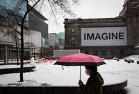A person wearing a face mask carries an umbrella as rain falls while walking past the snow-covered square outside the Vancouver Art Gallery in Vancouver, on Thursday, January 6, 2022.&nbsp;The agency that monitors British Columbia's waterways is warning of "minor to significant flooding" on B.C.'s Lower Mainland and Vancouver Island as warming temperatures and persistent rain melt heavy snow.&nbsp; THE CANADIAN PRESS/Darryl Dyck