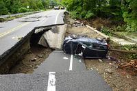 A damaged car lays on a collapsed roadway along Route 32 in the Hudson Valley near Cornwall, N.Y., Monday, July 10, 2023. Heavy rain has washed out roads and forced evacuations in the Northeast as more downpours were forecast throughout the day. (AP Photo/Paul Kazdan)
