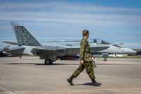 A Canadian forces member walks by a A CF-18 Hornet on the tarmac at Canadian Forces Base Trenton before an announcement by Minister of Defence Anita Anand in Trenton, Ont., on Monday June 20, 2022. THE CANADIAN PRESS/Lars Hagberg