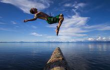 Jaron Piercy, 16, dives off a drift wood log repurposed as a diving board on the camping platform he engineered at Miracle Beach on Vancouver Island June 25, 2014. Photo by John Lehmann / The Globe and Mail