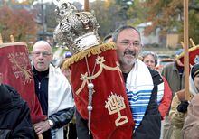 Richard Gottfried, center, carries the Torah as he and other members of the New Light Jewish congregation march along Denniston Street to their new home at 5898 Wilkins Avenue, Sunday, Nov. 12, 2017, in Pittsburgh. Robert Bowers went on trial Tuesday, May 30, 2023, more than four years after an attack on a Pittsburgh synagogue that killed 11 worshippers, including Gottfried, and wounded 7 others. Bowers could face the death penalty if convicted of some of the 63 counts he faces. (Pittsburgh Post-Gazette via AP)