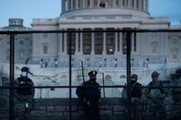 A Capitol Police officer stands with members of the National Guard behind a crowd control fence surrounding Capitol Hill a day after a pro-Trump mob broke into the US Capitol on January 7, 2021, in Washington, DC. (Photo by Brendan Smialowski / AFP) (Photo by BRENDAN SMIALOWSKI/AFP via Getty Images)