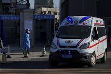 An ambulance passes a worker in protective gear outside a fever clinic in Beijing, Monday, Dec. 19, 2022. Chinese health authorities on Monday announced two additional COVID-19 deaths, both in the capital Beijing, that were the first reported in weeks and come during an expected surge of illnesses after the nation eased its strict "zero-COVID" approach. (AP Photo/Andy Wong)