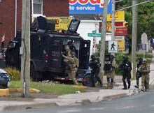 Emergency response officers enter a residence in Moncton, N.B., on Thursday, June 5, 2014. Three RCMP officers were killed and two injured by a gunman wearing military camouflage and wielding two guns on Wednesday. Police have identified a suspect as 24-year-old Justin Bourque of Moncton. THE CANADIAN PRESS/Andrew Vaughan