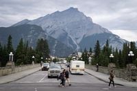 People walk across a street in Banff, Alta., in Banff National Park, Friday, July 21, 2017. THE CANADIAN PRESS/Jeff McIntosh