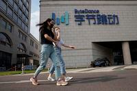FILE - In this Aug. 7, 2020, file photo, women wearing masks to prevent the spread of the coronavirus chat as they pass by the headquarters of ByteDance, owners of TikTok, in Beijing, China. TikTok's owner said Thursday, Sept. 24, 2020, that it has applied for a Chinese technology export license as it tries to complete a deal with Oracle and Walmart to keep the popular video app operating in the United States. (AP Photo/Ng Han Guan, File)
