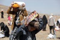 People carry aid they received from the local charity Mona Relief at a camp for internally displaced people on the outskirts of Sanaa, Yemen, on March 1, 2021.
