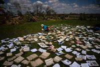 A teacher dries out books at a school that was heavily damaged by Hurricane Ian in La Coloma, in the province of Pinar del Rio, Cuba, Wednesday, Oct. 5, 2022. (AP Photo/Ramon Espinosa)