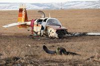 A small aircraft lies in a field next to the Trans-Canada Highway, within sight of the Springbank airport, after a crash west of Calgary, Friday, April 22, 2022. The Transportation Safety Board says it was likely a buildup of ice that caused the plane to crash and resulted in the death of its pilot and sent a passenger to hospital with life-threatening injuries. THE CANADIAN PRESS/Dave Chidley