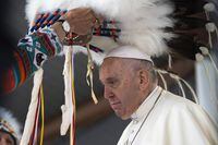 A headdress is placed on the head of Pope Francis following his apology for the residential school system at Maskwacis on July 25, 2022. 