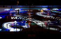 A worker moves a hockey net as Vancouver Canucks team logos are projected on the ice before the team's NHL hockey game against the Detroit Red Wings in Vancouver, B.C., on Thursday February 2, 2012. THE CANADIAN PRESS/Darryl Dyck