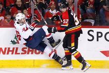 Washington Capitals' Nic Dowd, left, is knocked down by Calgary Flames' MacKenzie Weegar during first period NHL hockey action in Calgary, Ab., Saturday, Dec. 3, 2022. THE CANADIAN PRESS/Larry MacDougal